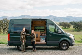 Jeune couple souriant devant un van en campagne