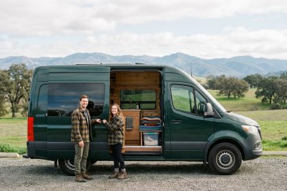 Jeune couple souriant devant un van en campagne