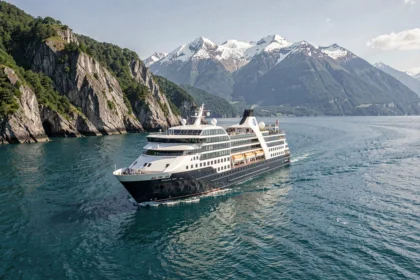 Bateau de croisière de luxe Le Ponant naviguant sur des eaux turquoise près d'une côte rocheuse spectaculaire