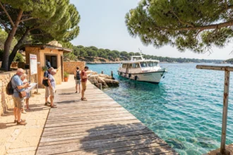 Embarcadère de l'île de Porquerolles avec ferry et panneau de réglementation, accès touristique 2026